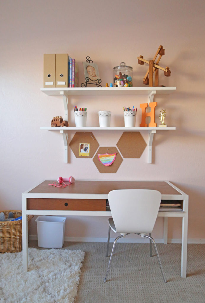 A light pink little girl's room with gold, wood, and coral accents