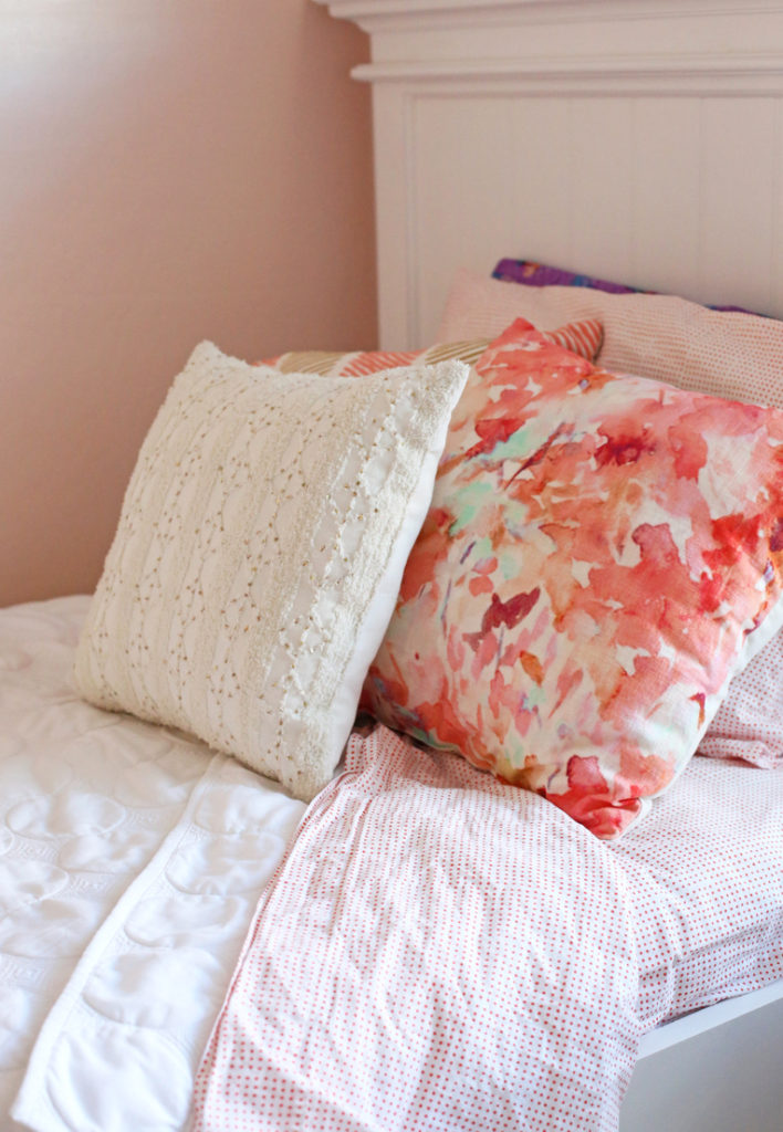 A light pink little girl's room with gold, wood, and coral accents