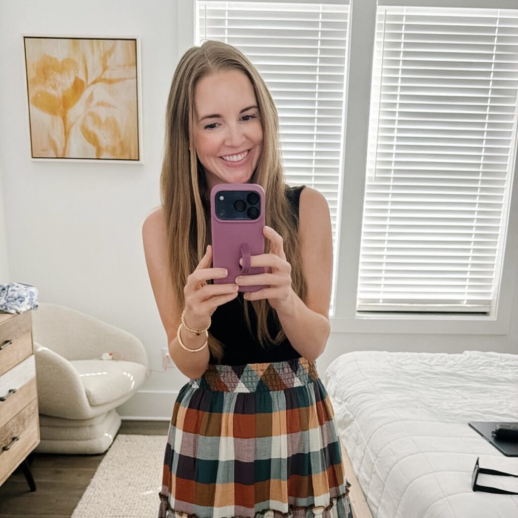 woman taking a selfie wearing a plaid skirt and black tank top